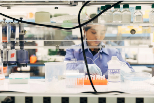 Scientist behind glass shelving working in a lab