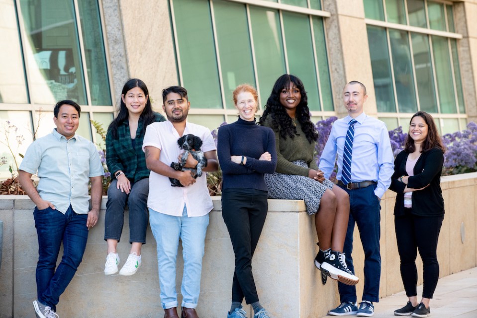 seven people (one holding a puppy) smile at camera