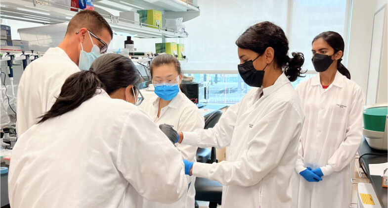 Group of science researchers wearing masks and working in a lab
