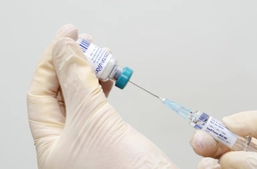 Close up of person drawing vaccine into a syringe.