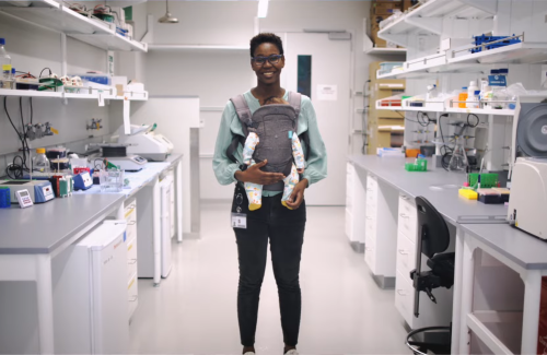woman posing in science lab with baby in front carrier