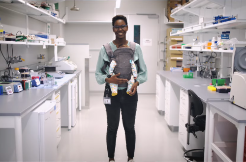 woman posing in science lab with baby in front carrier
