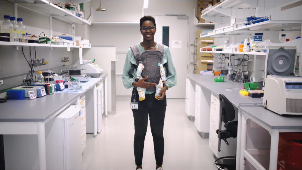 woman posing in science lab with baby in front carrier