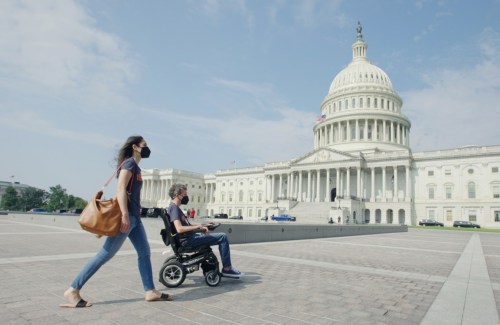 Woman pushing a man in a wheelchair in front of the Capitol Building in Washington, D.C.