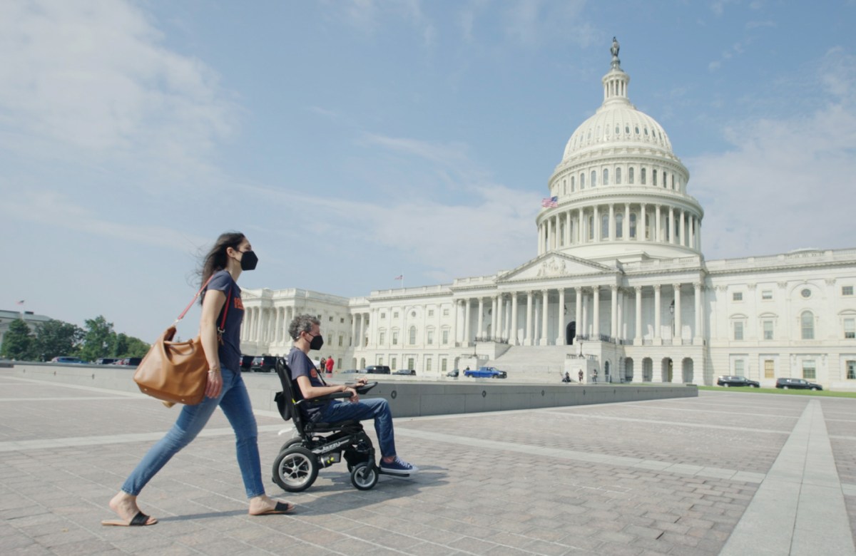 Woman pushing a man in a wheelchair in front of the Capitol Building in Washington, D.C.