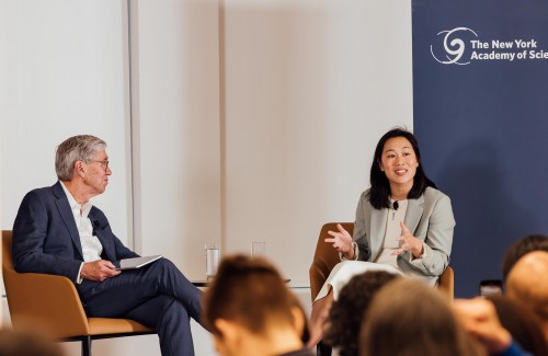 Drs. Richard Lifton and Priscilla Chan sit side-by-side in armchairs on stage.